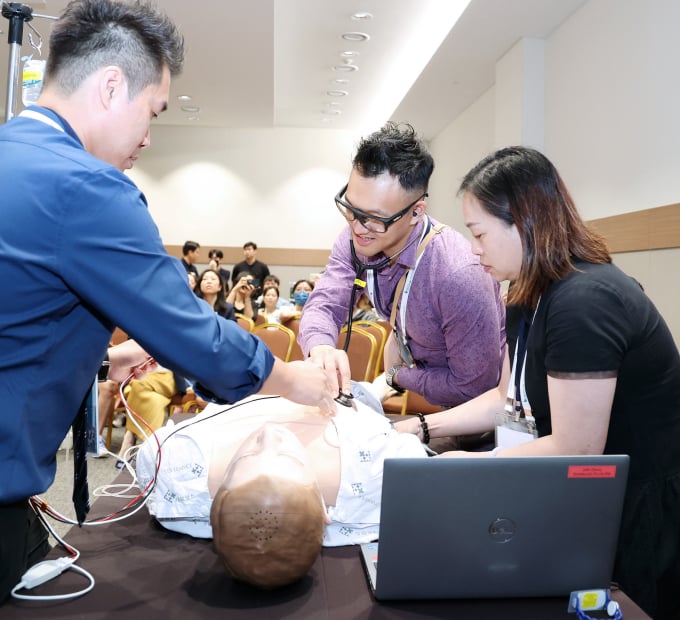 Medical trainees perform hands-on procedure on mannequin during live demonstration.