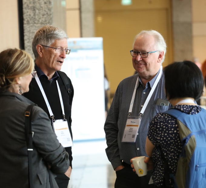 Four people standing and talking during a conference networking break.