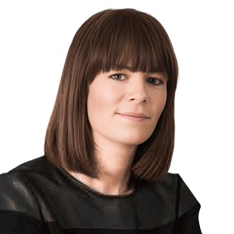 Eadin Murphy with shoulder-length brown hair, wearing a black top against a black background.