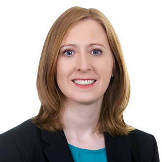 Elaine O’Connor with shoulder-length light brown hair, wearing a black blazer over a teal top, posing against a black background.