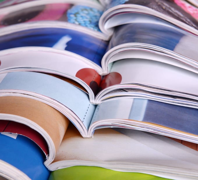 Stacked open magazines with colorful images and glossy pages.