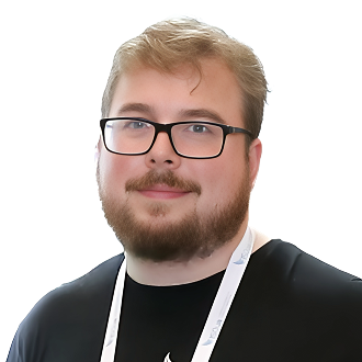 Luke Dunne in a black shirt with white lanyard, standing against a black background.