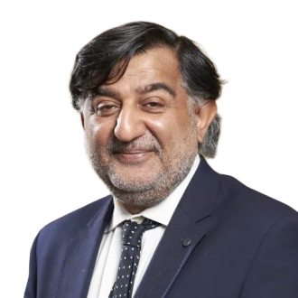 Sir Aziz Sheikh in a dark suit and polka dot tie, posing formally against a black background.