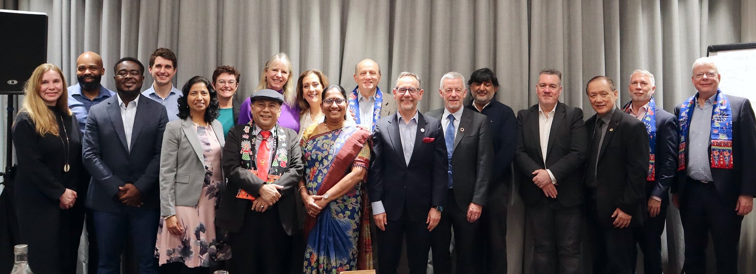 Diverse group of people in formal and traditional outfits posing together at a cultural event.