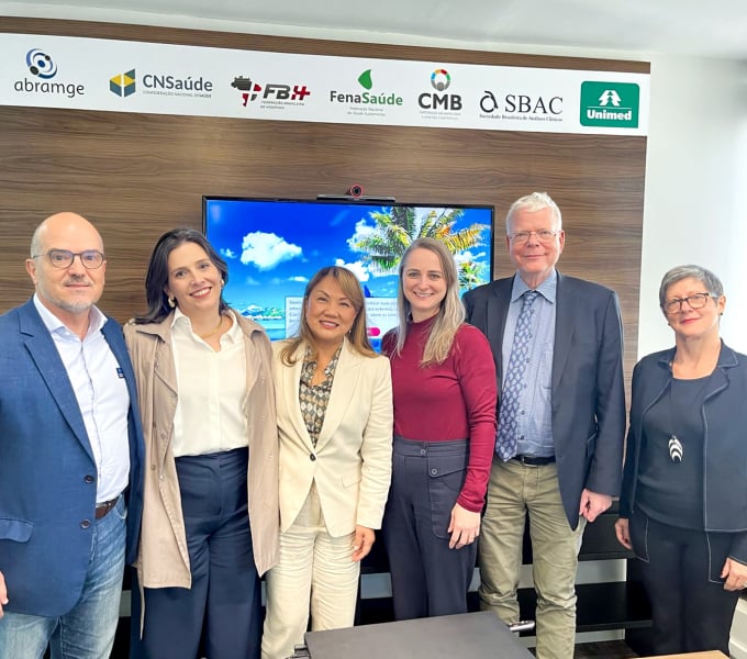 A group of six smiling professionals standing in a meeting room.