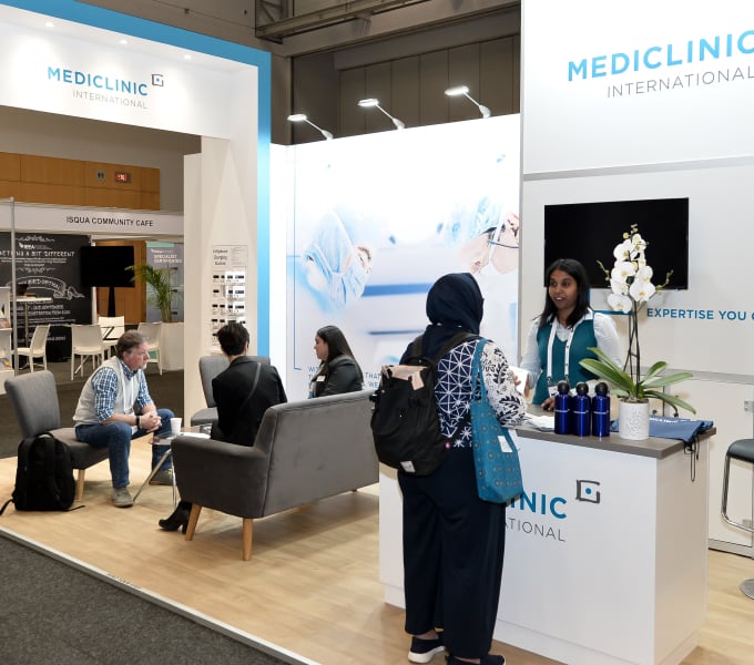 A woman at the Mediclinic International booth talking to an attendee.